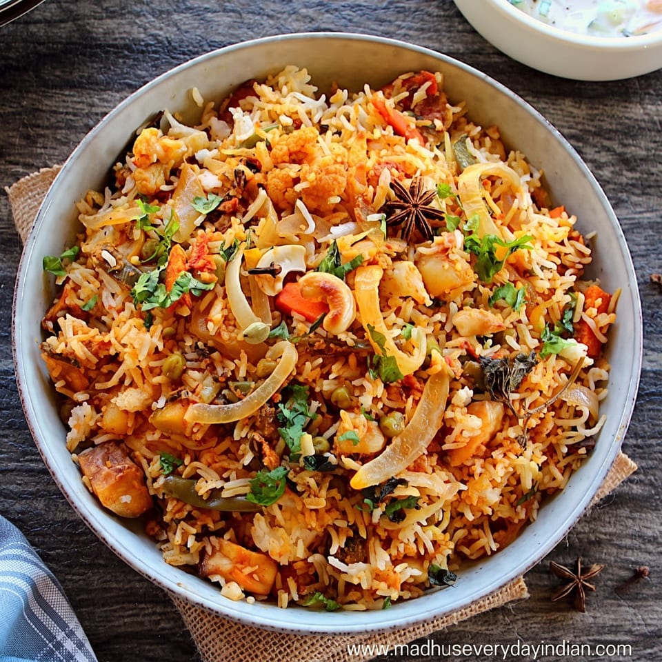 Close-up of a bowl of vegetable biryani with rice, vegetables, and spices on a wooden table.